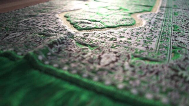 cinematic camera movement over a green Muslim prayer rug, focusing on texture, traditional patterns