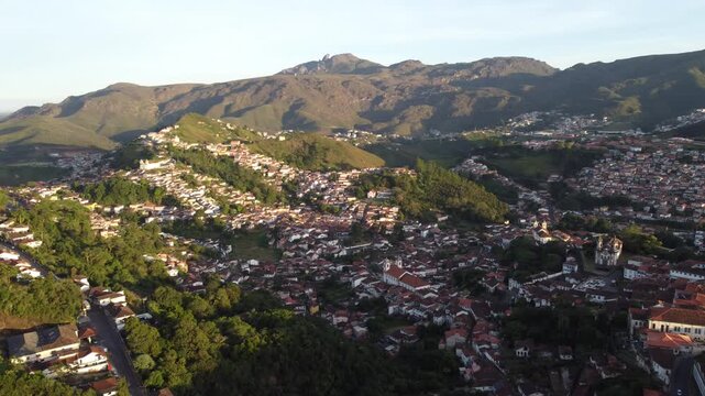 Aerial views of Ouro Preto, Brazil, at sunset, featuring the historic colonial town, iconic churches, rolling mountains, traditional architecture, and the warm light of the golden hour.