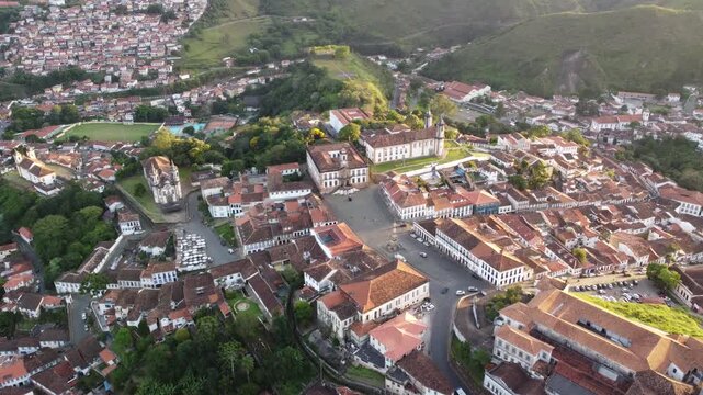 Aerial views of Ouro Preto, Brazil, at sunset, featuring the historic colonial town, iconic churches, rolling mountains, traditional architecture, and the warm light of the golden hour.