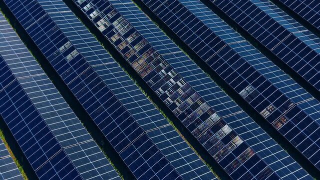 Overhead view of solar panel rows at photovoltaic farm. Diagonal dark blue modules with grid pattern filling the frame.