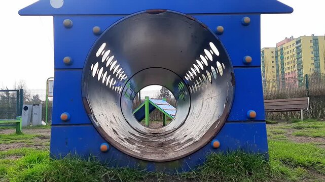 Mixed breed dog running out of agility tunnel during training session. Pet performing obstacle course trick on outdoor dog playground. Dog training, exercise, obedience, recreation