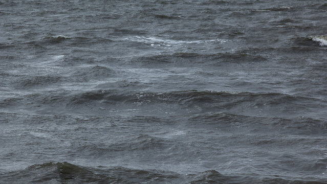 Wind‑driven ripples forming shifting patterns on dark open water 