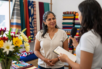 Fototapeta premium Latina Woman Interviewed by Young Journalist at Craft Market