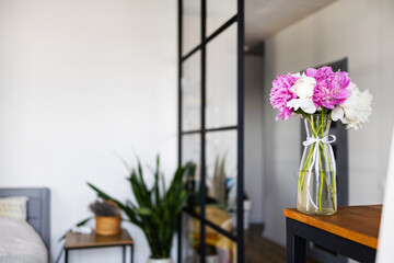Fototapeta premium Pink and white peonies in a vase on a wooden table for a cozy home interior design or lifestyle blog decoration concept