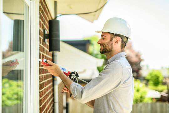 Construction worker uses sealant gun during window installation