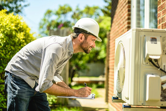 technician working on air conditioning or heat pump outdoor unit inspection or repair