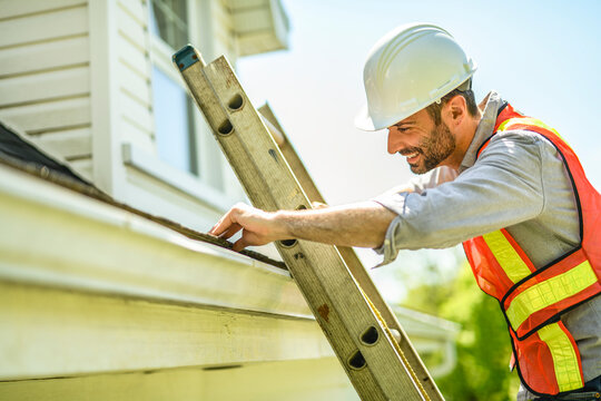 Man with a white hard hat holding a clipboard, inspect house