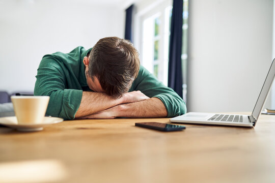 Overworked man sleeping on arms at desk