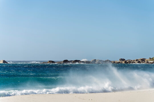 Crashing wave on the sandy beach of Camps Bay in Cape Town