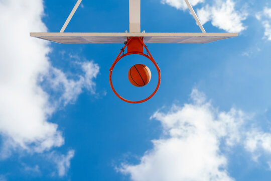 Basketball and hoop, blue sky, upward view