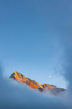 Mountain peak above clouds with crescent moon in Vorarlberg