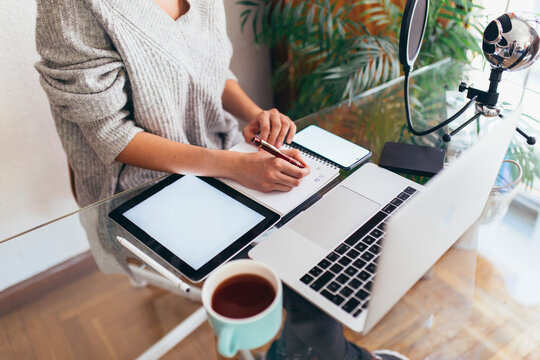 Podcaster writing in diary at desk in home office