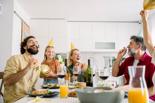 Family enjoying birthday celebration at home with party hats and food
