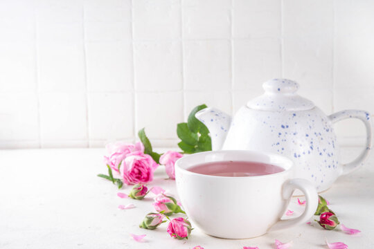 Healthy non caffeine drink, herbal rose tea with fresh organic rose petals, hot infused tea beverage on white background copy space