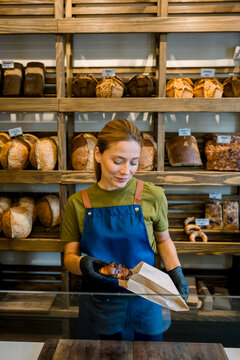 Bakery owner standing behind counter selling bread confidently