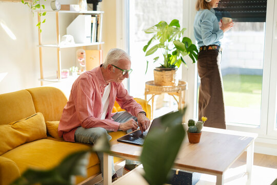 Couple using laptop and drinking coffee in modern living room