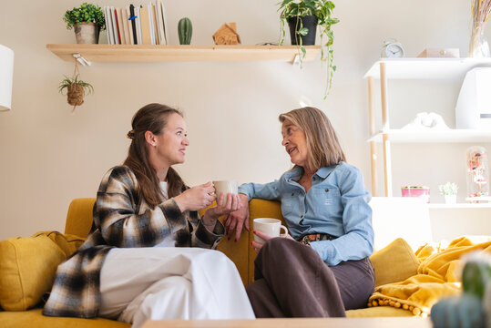Mother and daughter talking and drinking coffee at home