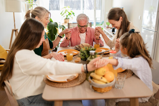 Multi-generational family praying together at home before breakfast