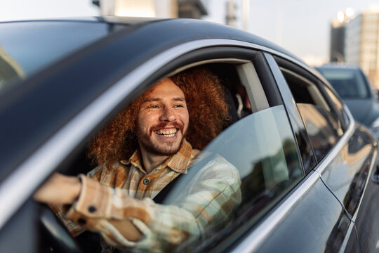 Happy curly haired man sitting in car
