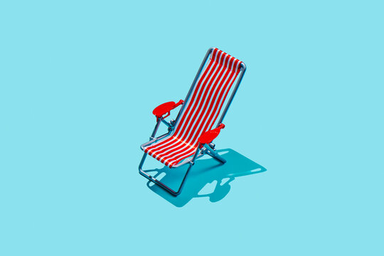 Empty striped beach chair on bright turquoise background