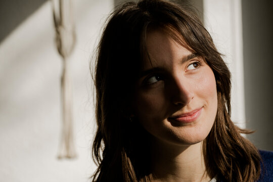 Smiling student daydreaming at home in sunlight
