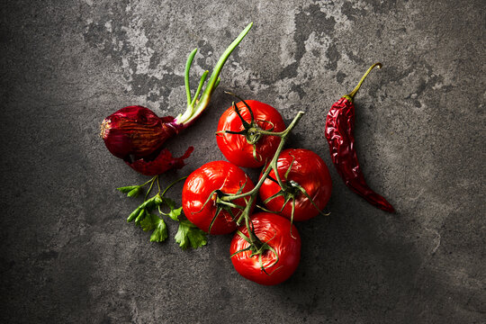 Withered tomato and onion on dark stone background