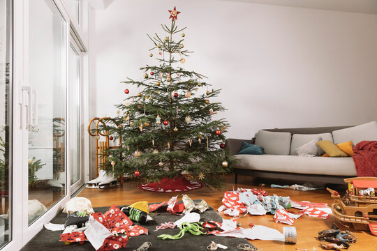 Living room on Christmas morning with torn up wrapping paper in front of the tree
