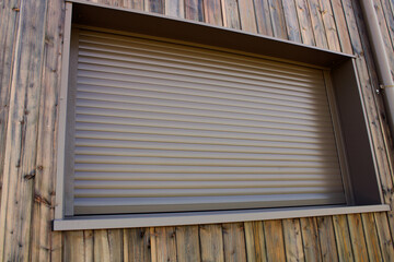 Volet roulant de fenêtre marron sur la façade de la maison en bardage bois