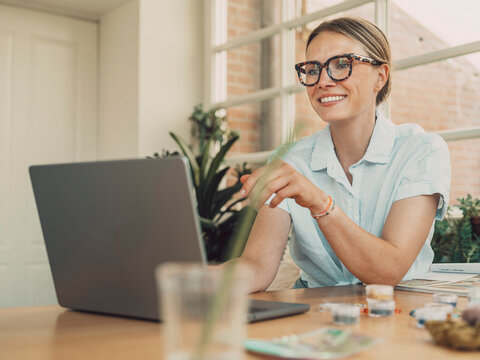 Happy artisan woman crafting with pearls at home office desk