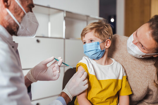 Boy looking at doctor holding vaccine injection in center