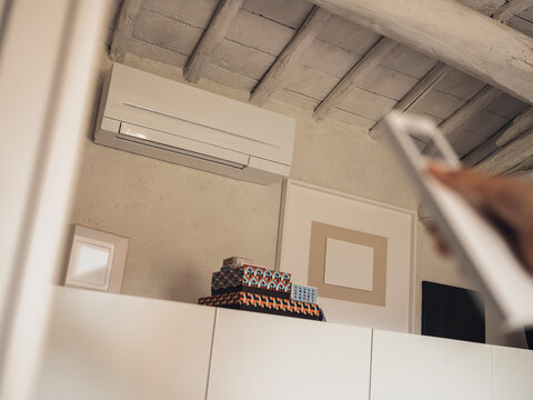 Hand holding remote to control air conditioner at home