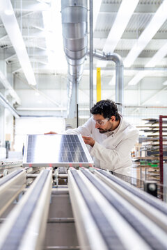 Engineer inspecting solar panel in a factory setting