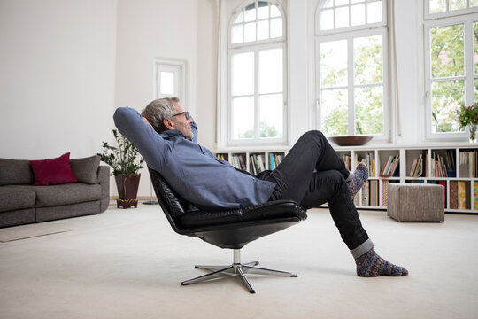 Relaxed mature man at home sitting in chair