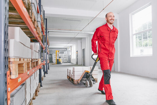 Smiling man in warehouse pulling pallet jack