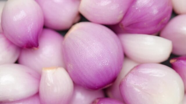 Whole fresh peeled Thai shallots slowly rotating, Top view shot
