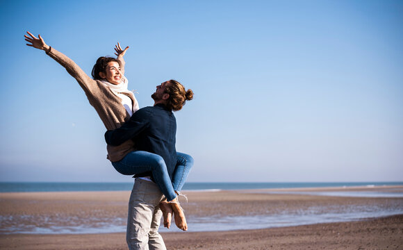 Happy couple enjoying holiday at the beach with man lifting woman