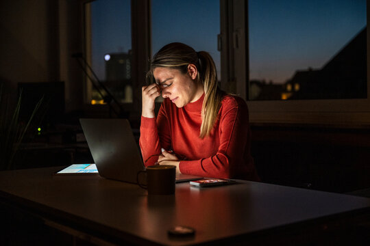 Stressed entrepreneur working late evening in dark office