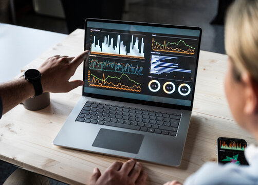 Business team discussing finance data on laptop screen at office desk