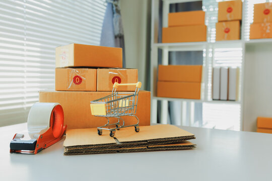 SME inventory control and stock organization system layout with miniature hand truck, delivery boxes, and stationery on a desk.