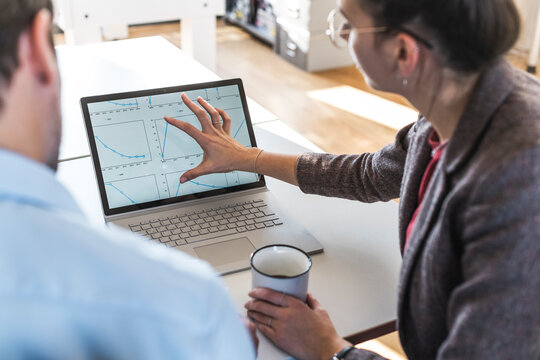 Businesswoman pointing at laptop chart during office meeting