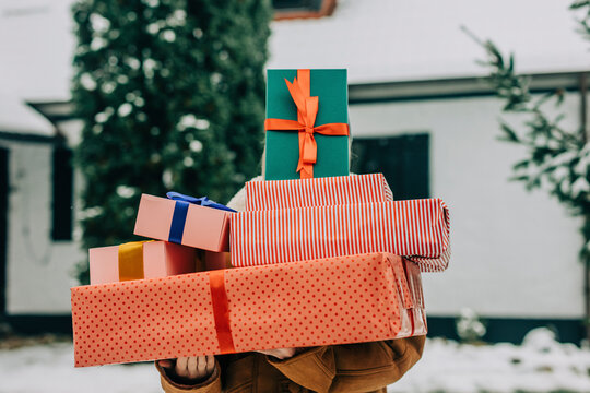 Woman covering face with Christmas presents in winter