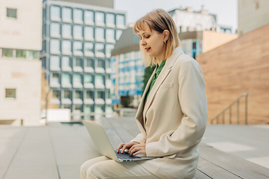 Businesswoman working on laptop while sitting on city bench outdoors