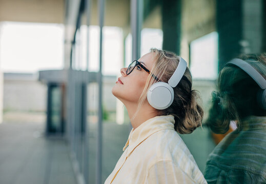 Businesswoman relaxing with music on headphones outside office
