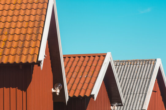 Roofs on boat houses in Fjallbacka village, Sweden, showing different styles against clear blue sky