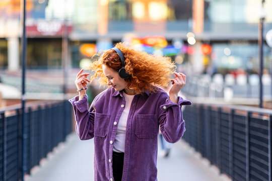 Woman wearing headphones dancing on bridge