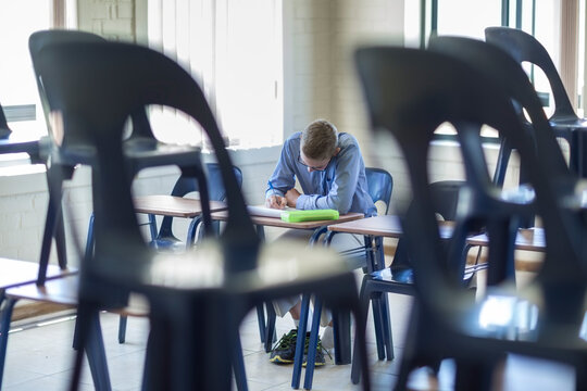 Schoolboy writing in classroom