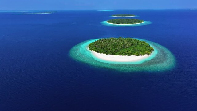Aerial view of lush tropical islands with white sand beaches surrounded by turquoise coral reefs and deep blue ocean water in Kendhoo, Baa Atoll, Maldives.