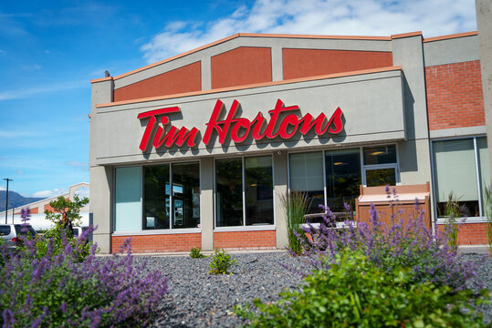 Tim Hortons fast food location with beautiful purple flowers in front of the restaurant on a sunny day.