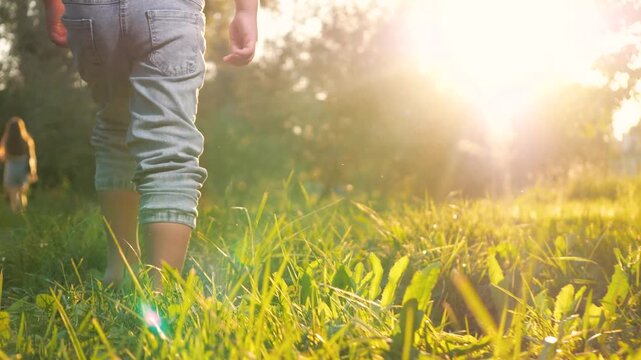 Little contented child joyfully dashes barefoot on grass in park during warm weather. In meadow gleeful child boy sprints shoeless across lush greenery. Happy kid runs cheerfully across grass