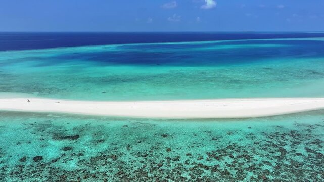 Aerial view of a pristine white sandbank surrounded by turquoise waters and coral reefs in the Indian Ocean at Kendhoo, Baa Atoll, Maldives.